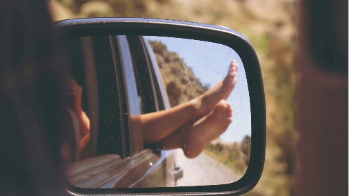 best cars for road trips and camping - feet hanging out of a car window seen through a wing mirror